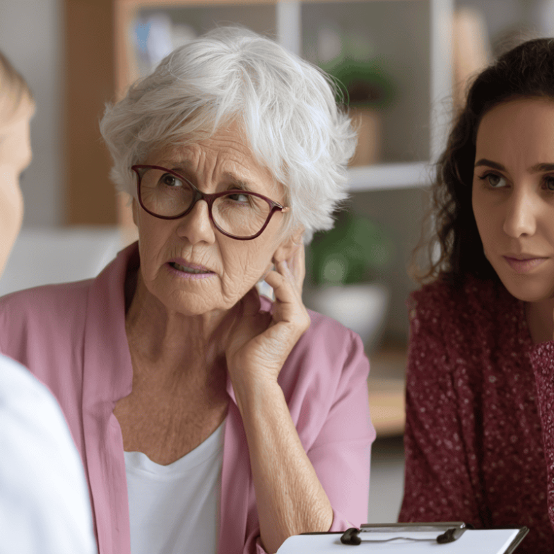 Older woman and adult daughter listening attentively during a medical consultation with a healthcare provider